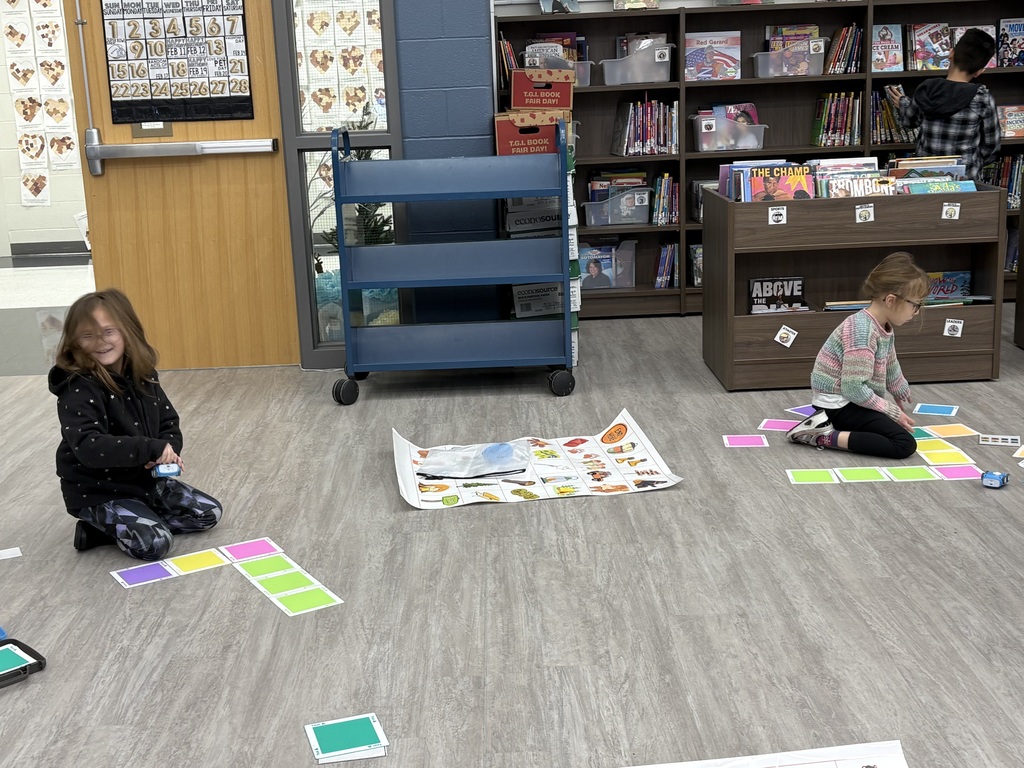 A student using a car robot and colored floor tiles. 