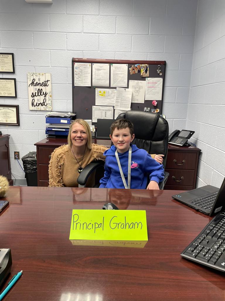 Second grader Graham Riva takes a picture with Dr. Deb Coberley in her office.