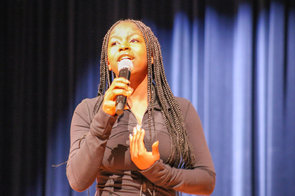 student with long braids sings on stage