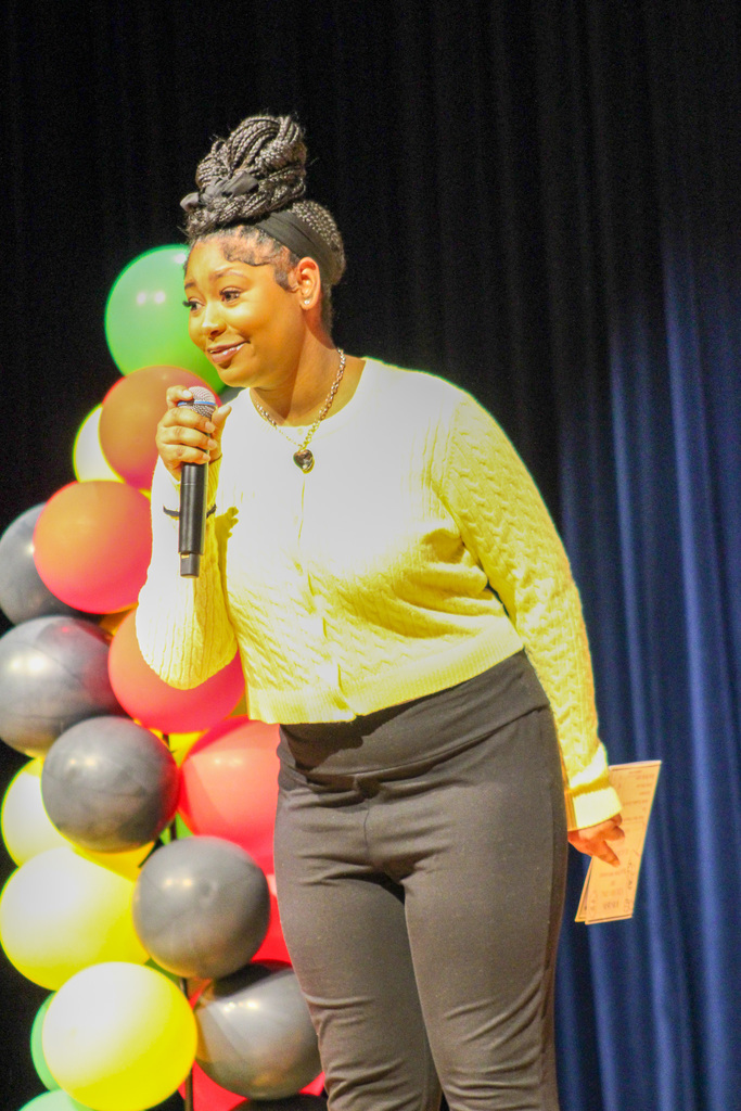 student stands on stage holding microphone