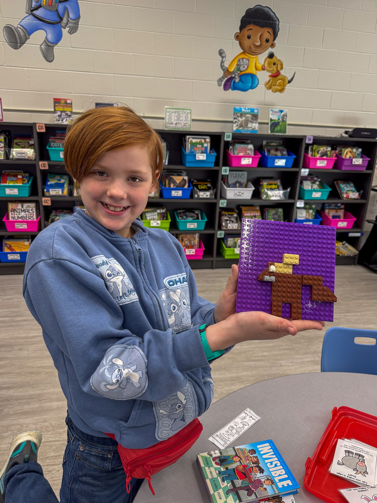 elementary school student holds Lego animal on purple background