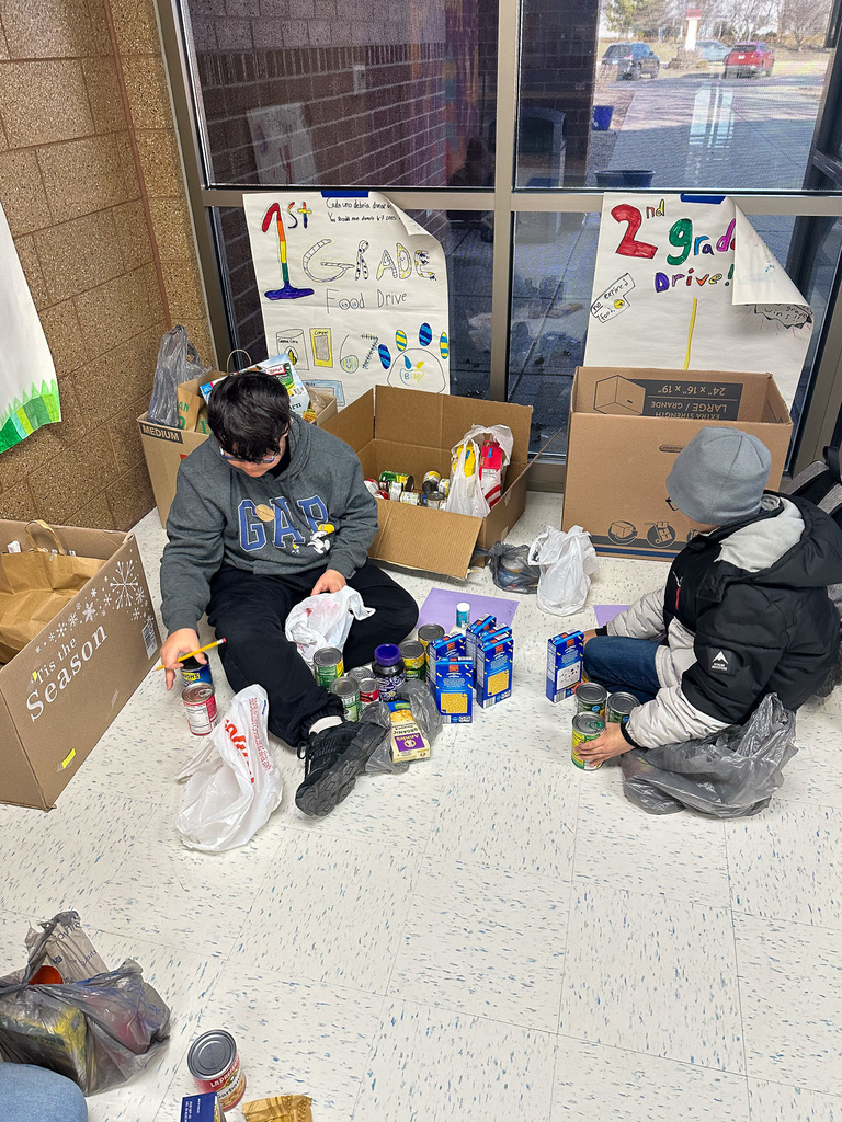 two students sit on hallway floor sorting canned goods