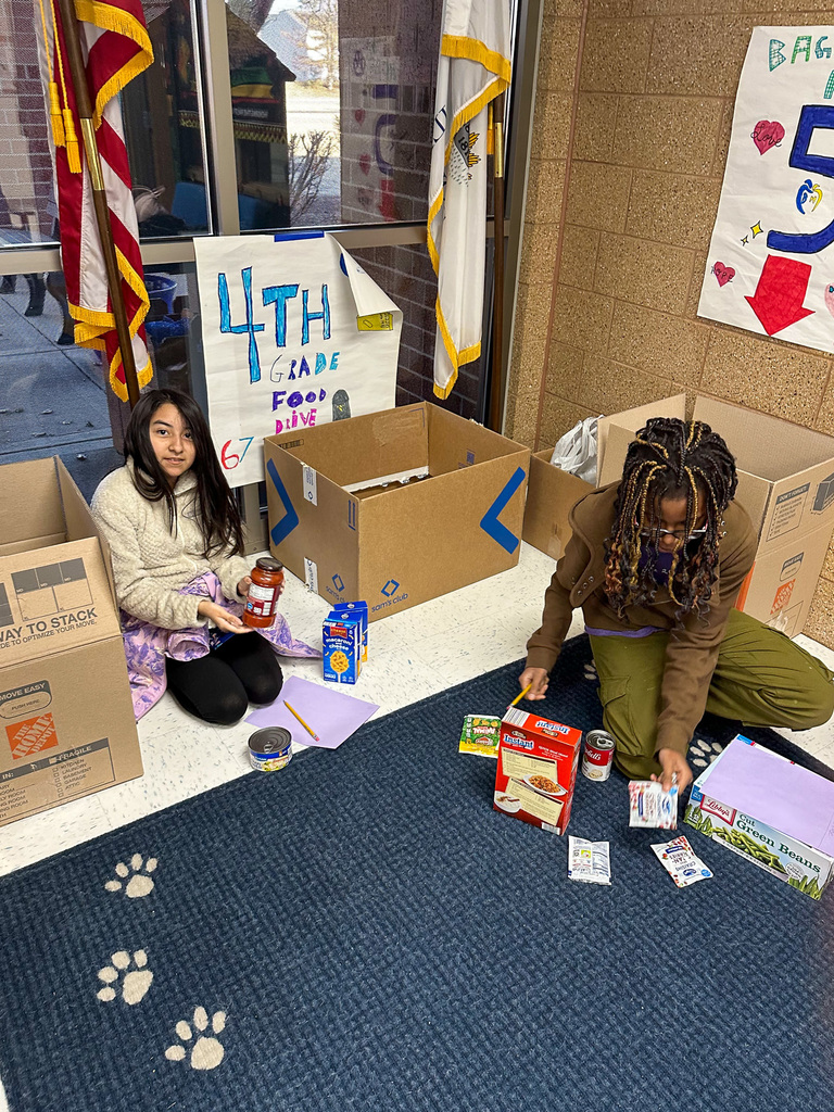 two students sort and box canned good on floor