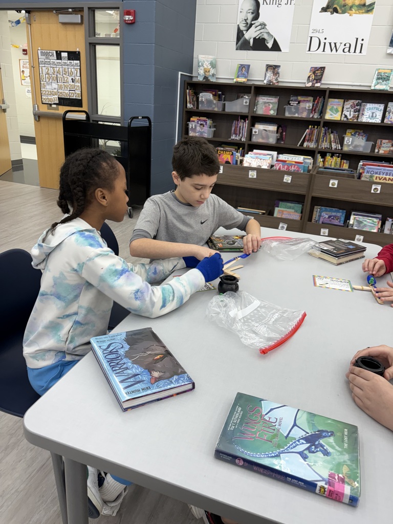 Students building a catapult  in the media center. 