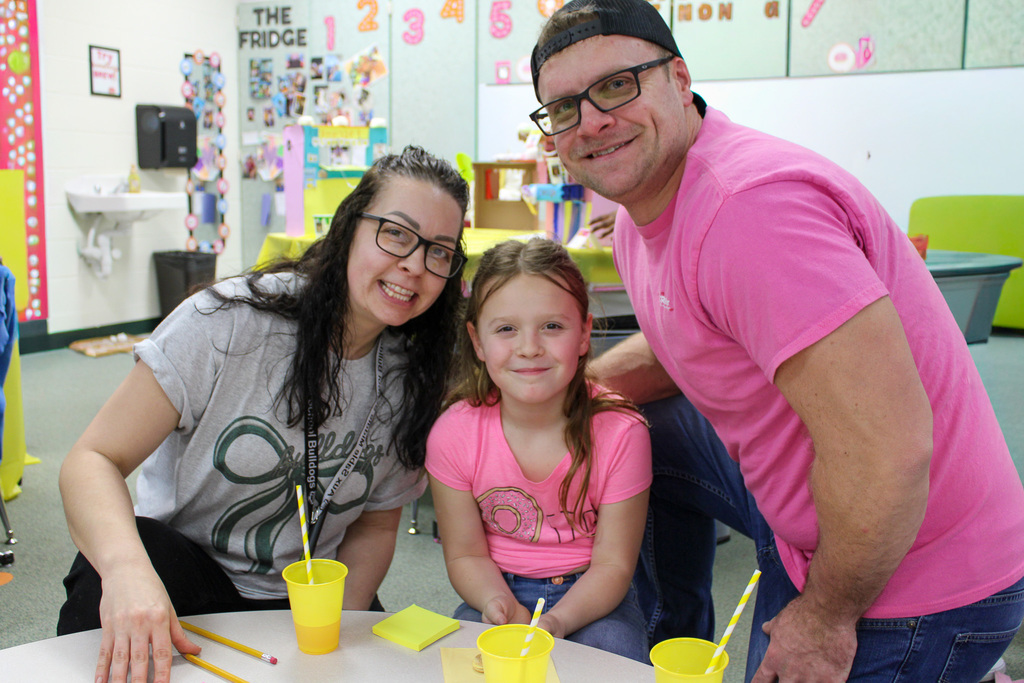 man and woman pose with girl seated at table