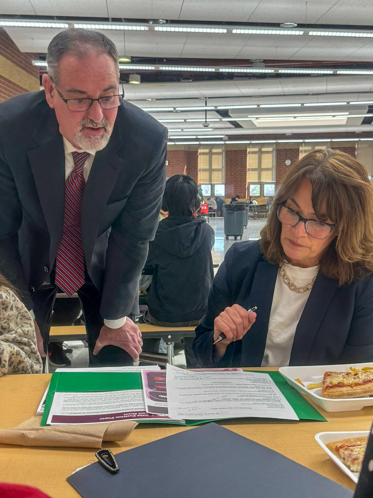 District 202 school superintendent Dr. Glenn Wood looks over Illinois State Senator Meg Cappel's shoulder talking about a a paper in front of her