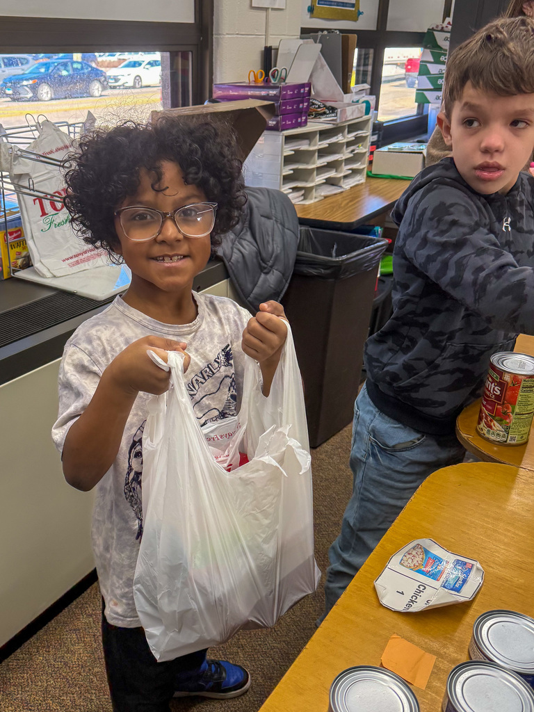 an elementary school students holds a bag of canned goods