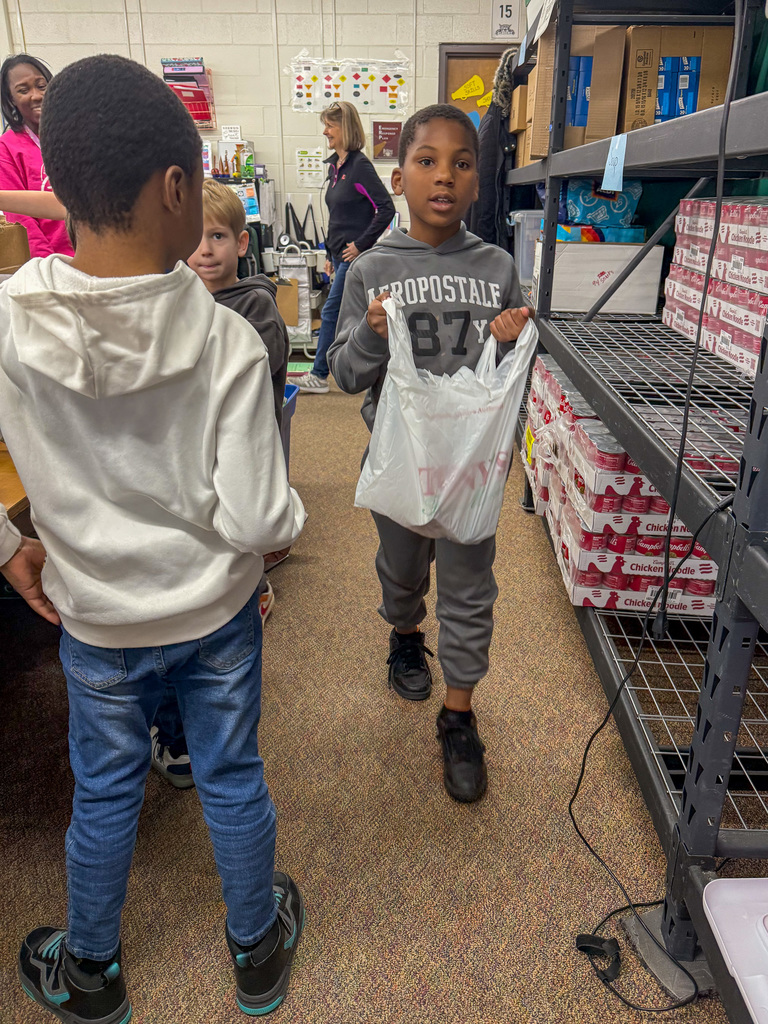 Elementary schools student carries plastic bag of food 