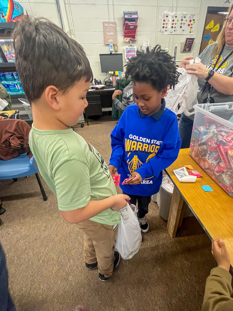two elementary school male students put canned goods into a plastic bag