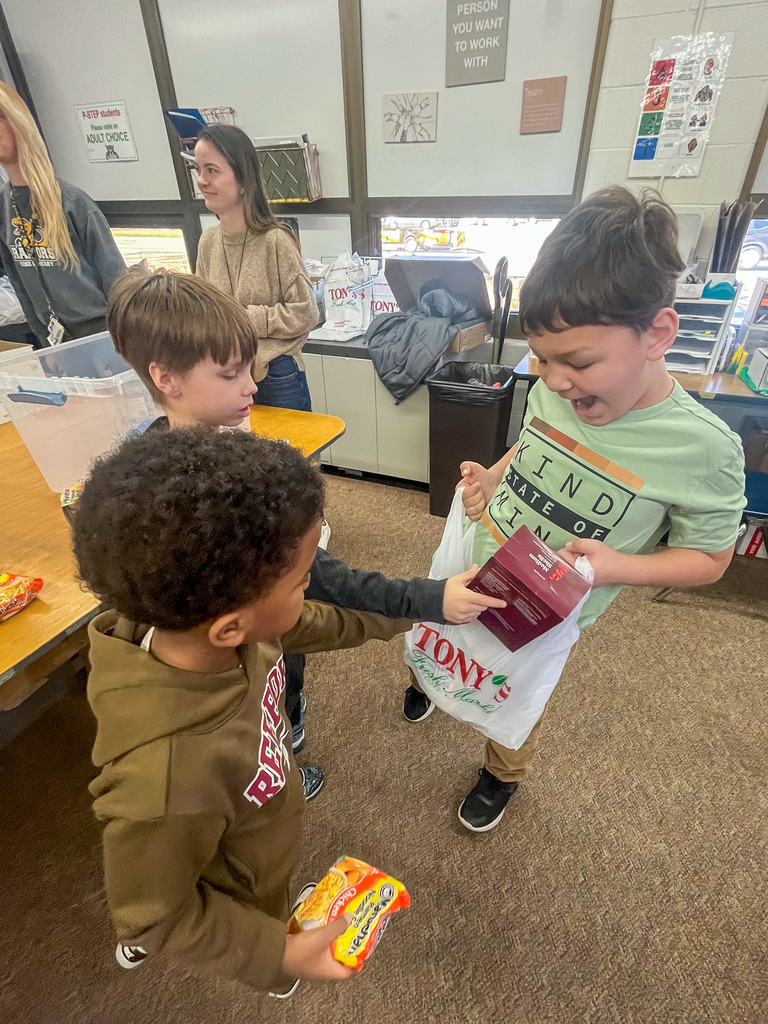 three elementary school students put food into a plastic bag