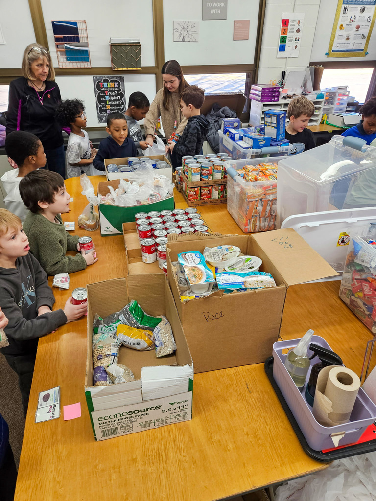 group of elementary school students work with adults to pack canned goods