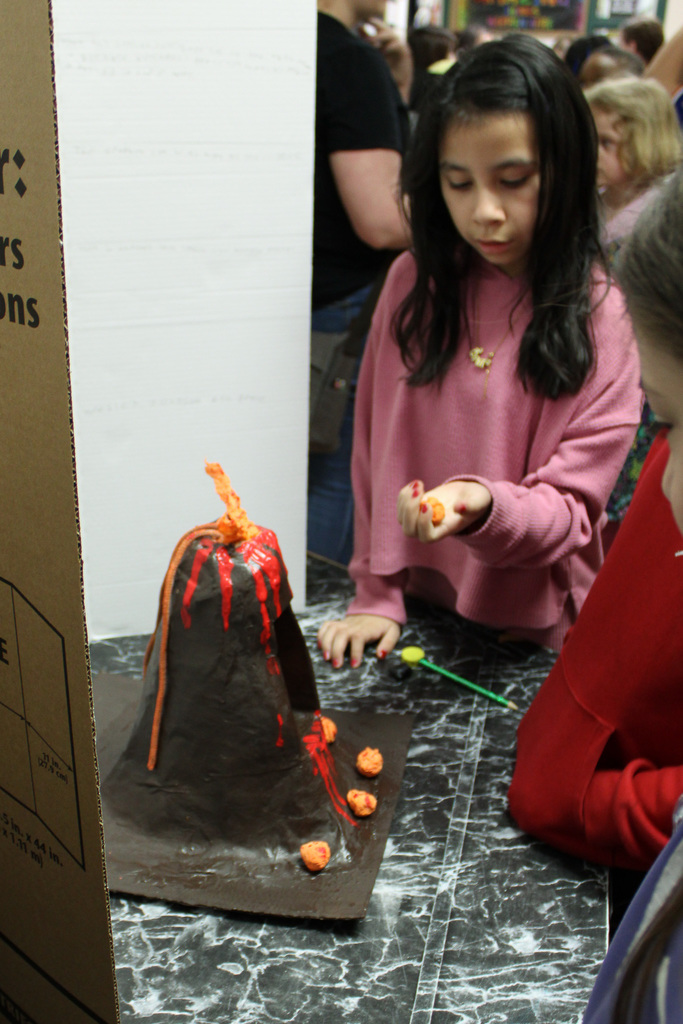 girl holds fake lava in hand from a volcano science experiment