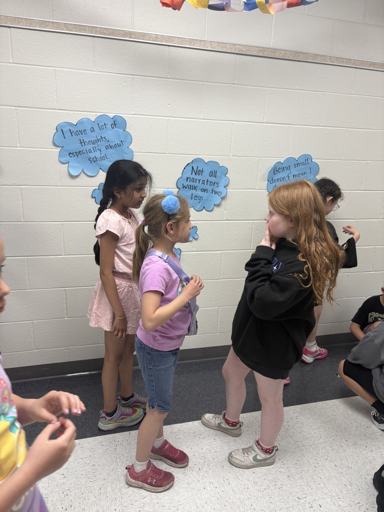 Three students in the hall discussing a poster. 
