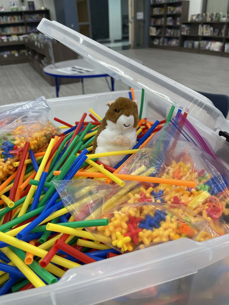 A small stuffed hamster in a bin of building straws