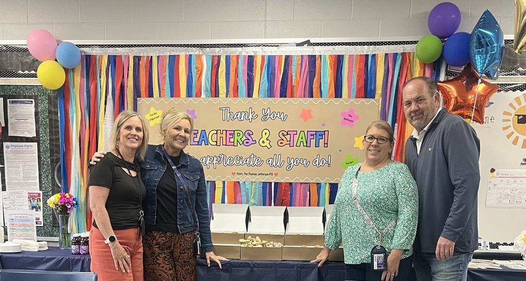 4 adults standing in front of a table with a sign behind it that says thank you teachers and staff.