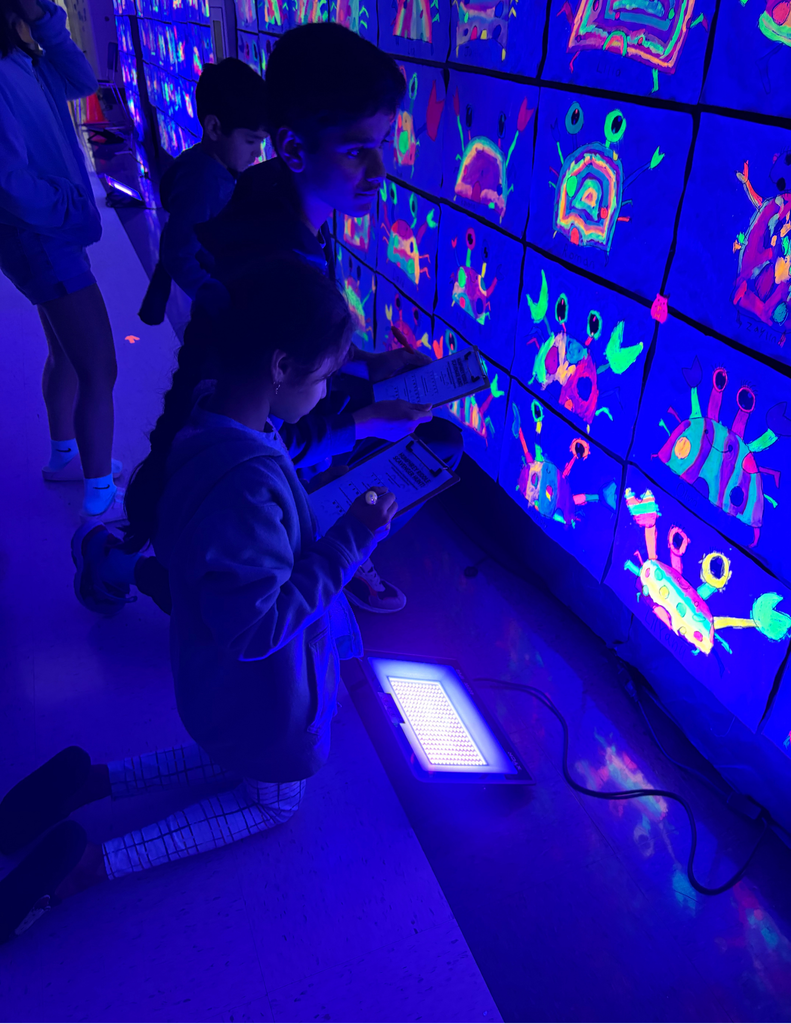 Two students standing in front of glow in the dark art.