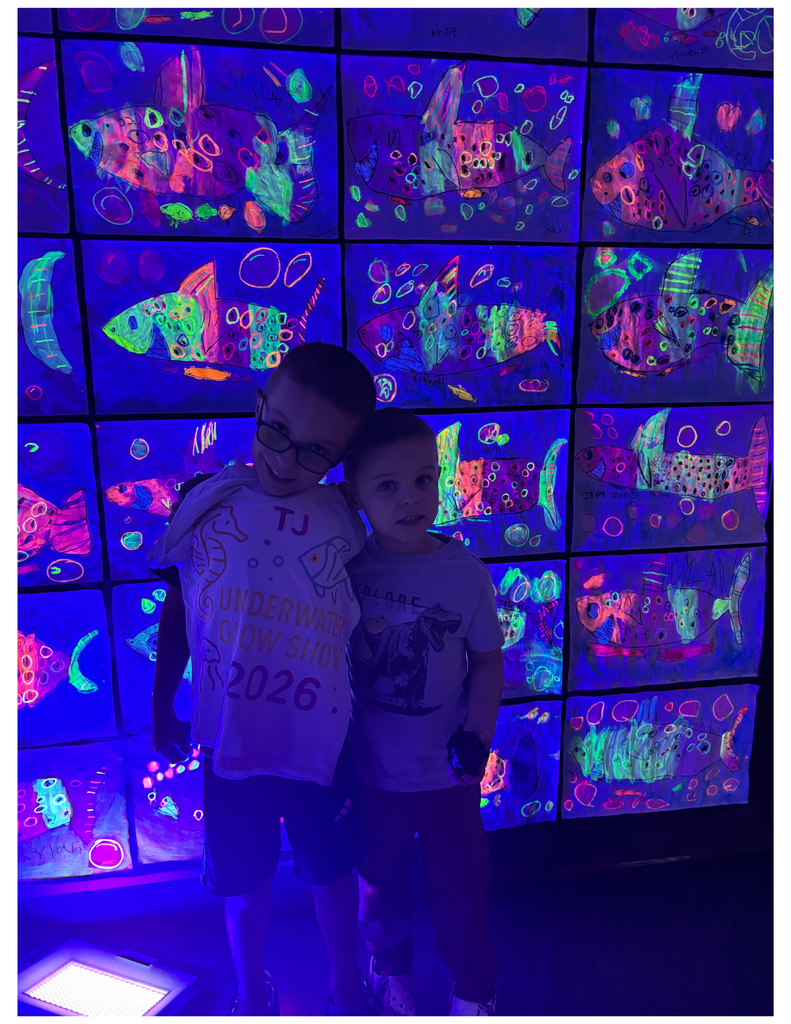 Two students standing in front of glow in the dark art.