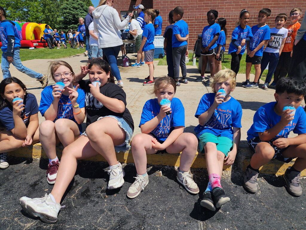 Students sitting on a curb outside. 