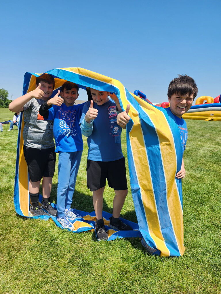 Four students outside under a towel. 