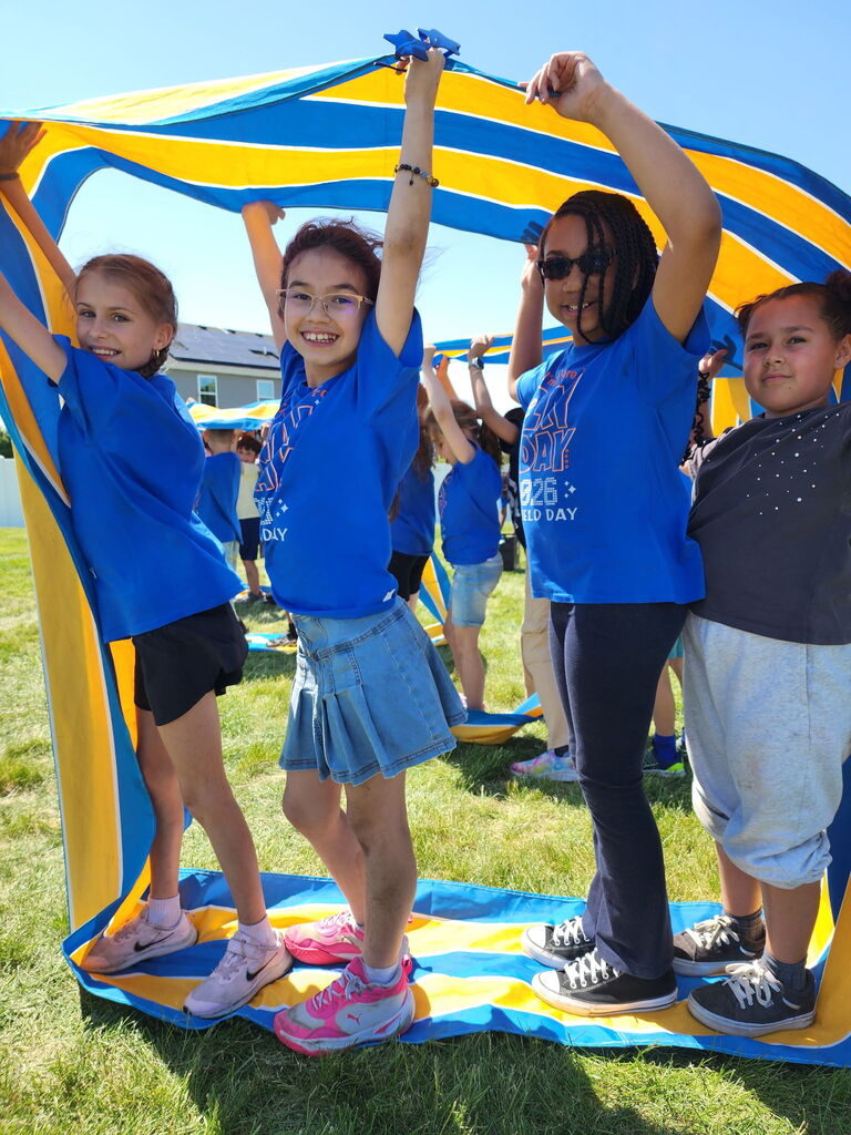 Four students standing outside under a towel.