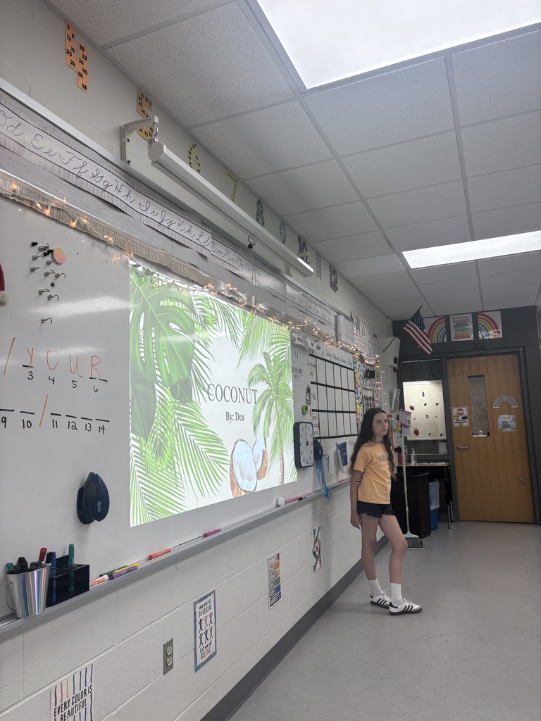 A student standing in front of a presentation in a classroom. 