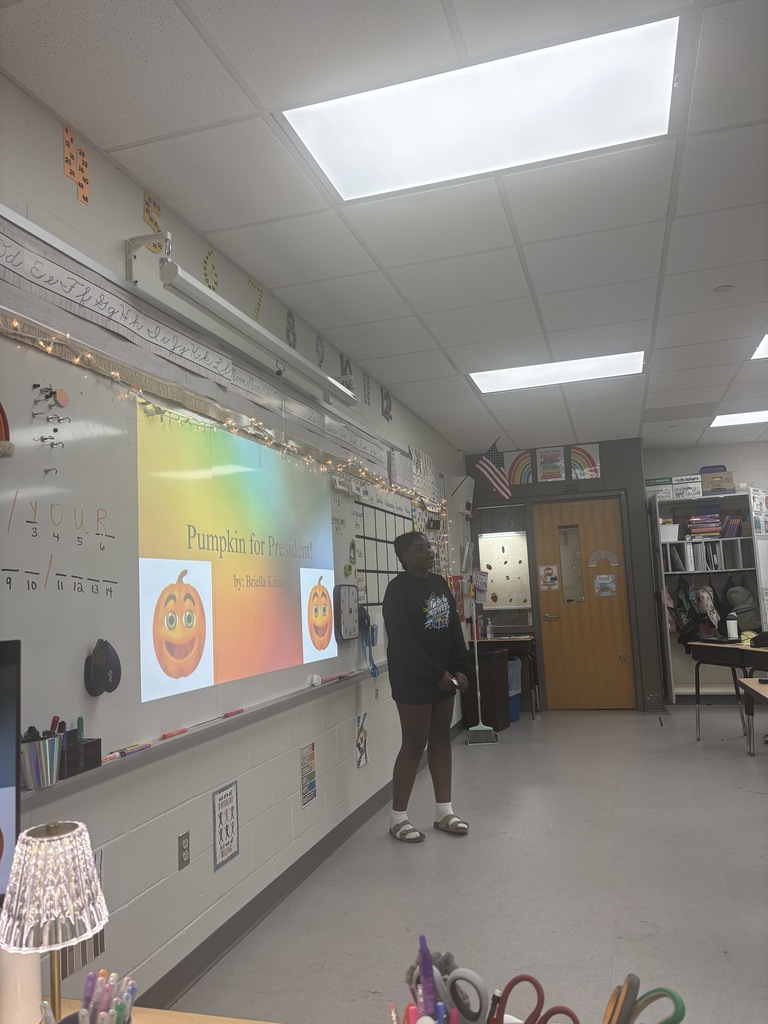 A student standing in front of a presentation in a classroom. 