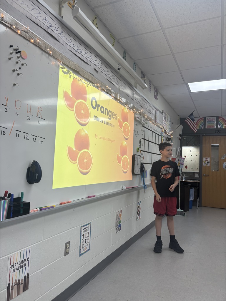 A student standing in front of a presentation in a classroom. 