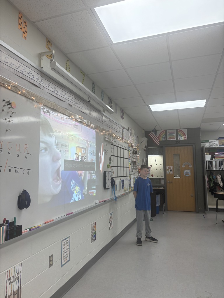 A student standing in front of a presentation in a classroom. 
