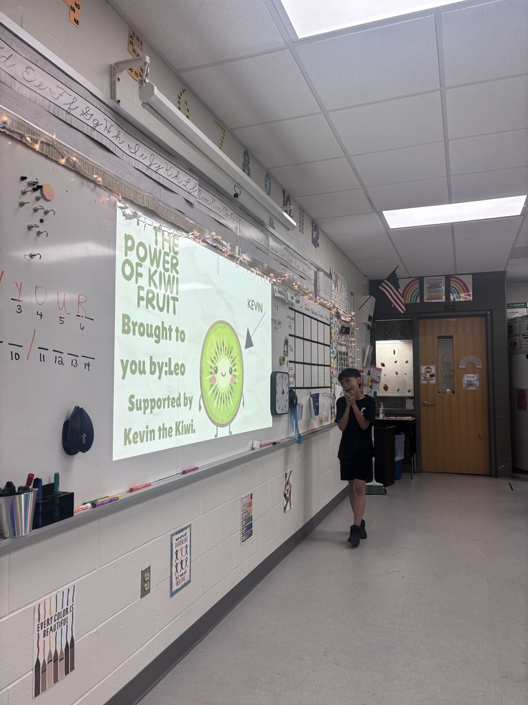 A student standing in front of a presentation in a classroom. 
