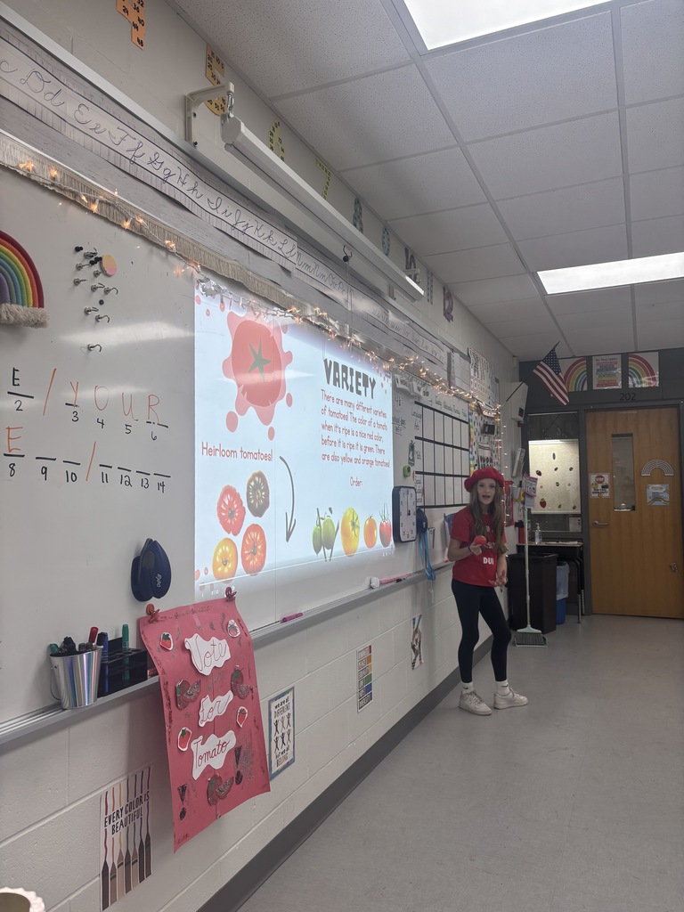 A student standing in front of a presentation in a classroom. 