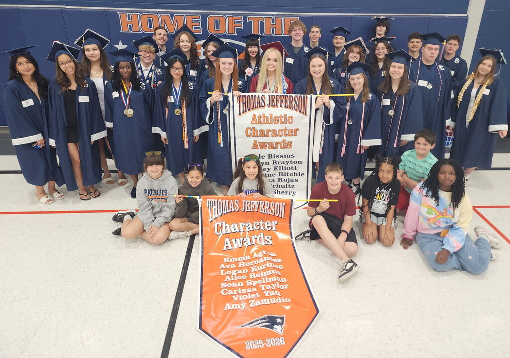 Students in graduate caps and gowns posing in a gym.