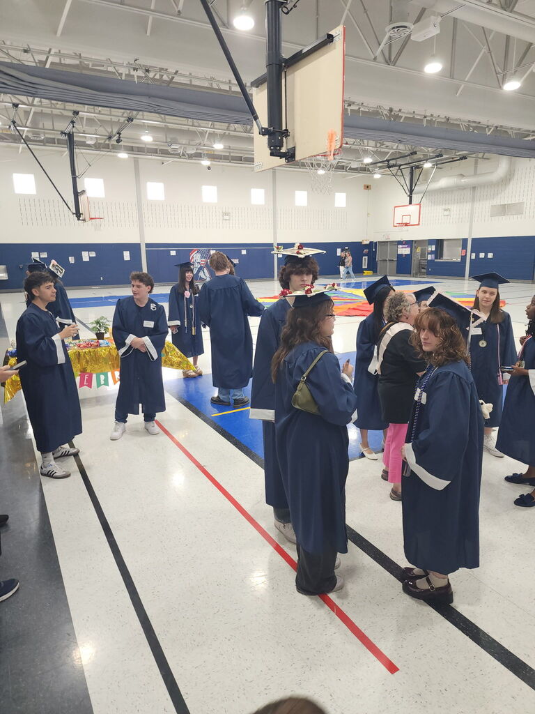 Students in caps and gowns standing in a gym 
