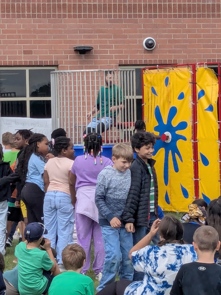 Principal Tyler Haymond takes a splash in a dunk tank outside with students watching. 