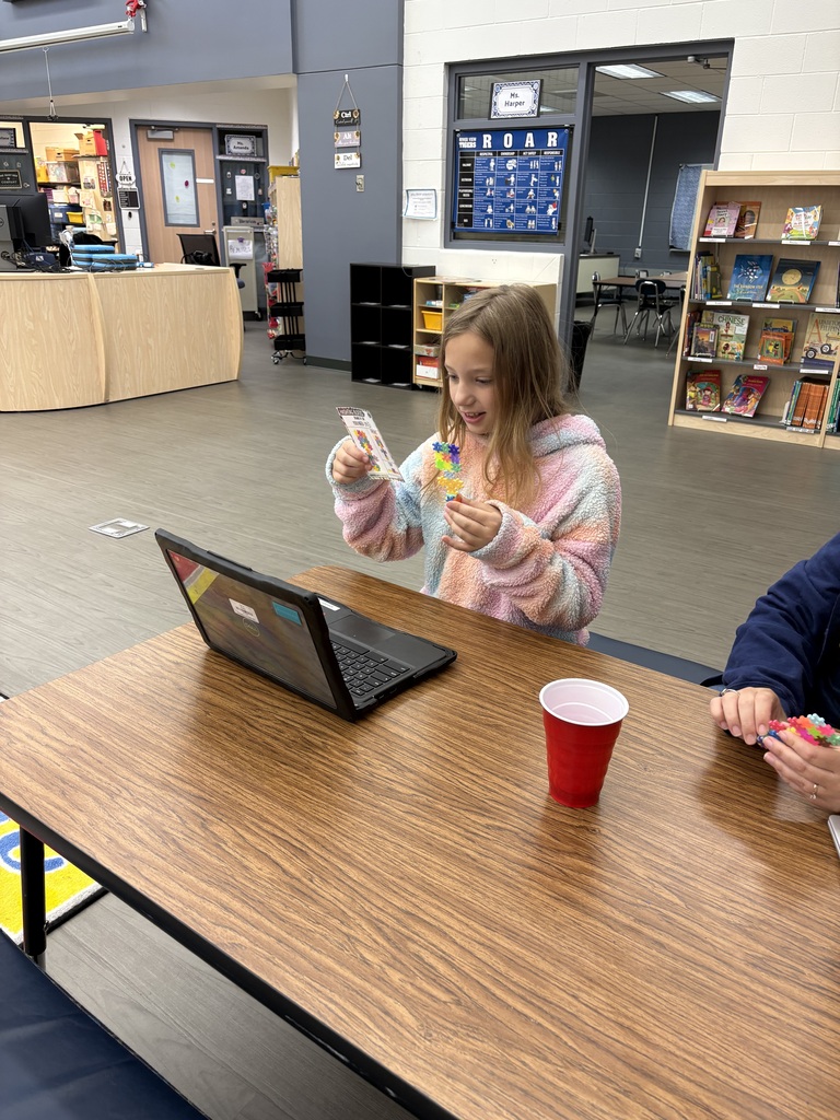 girl holding up card in front of laptop