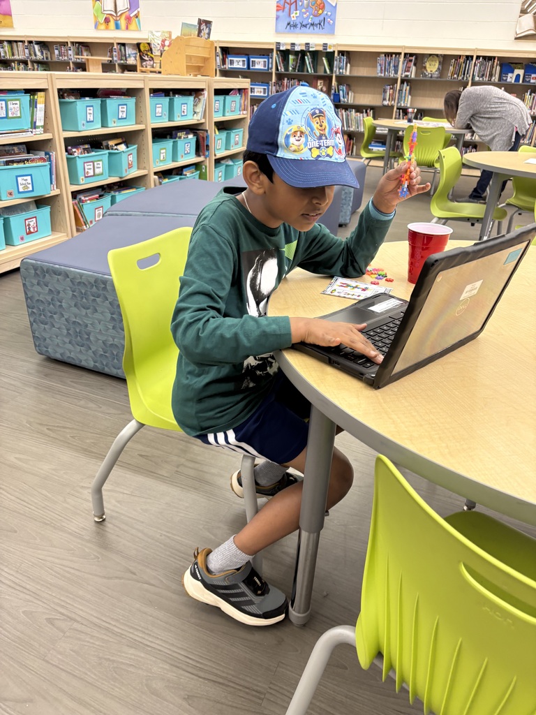 student holding up colorful building blocks in front of laptop
