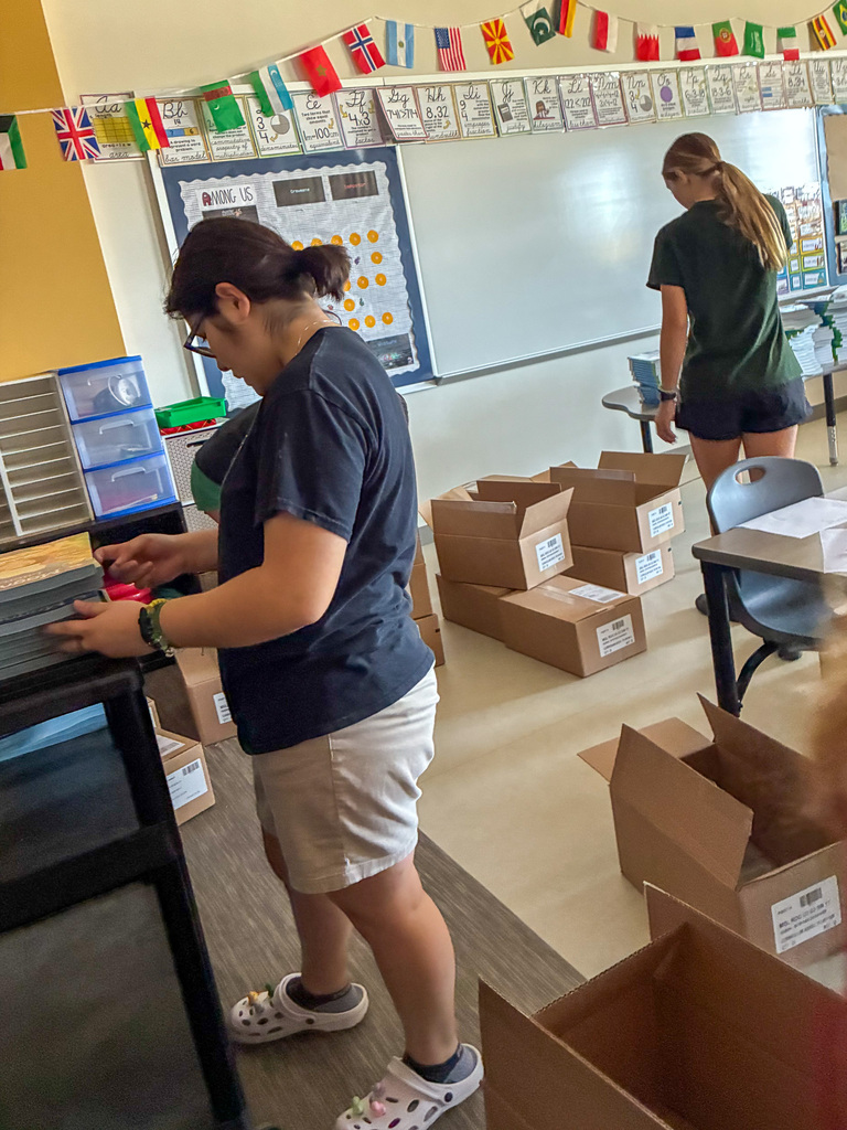 two high school girls catalog books in a classroom
