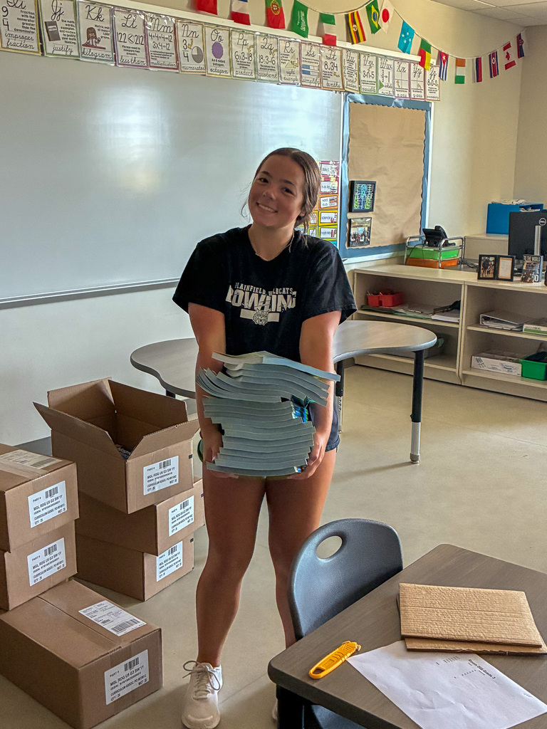 high school girl holding books in classroom