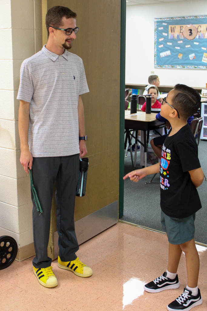 teacher stands in doorway talking to student