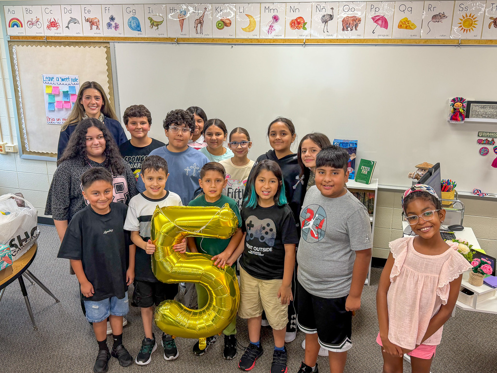 group of student standing holding golden 5 balloon