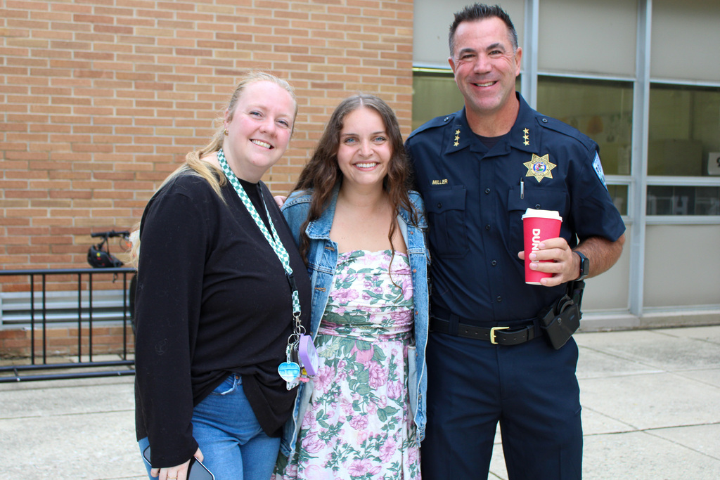 two teachers pose with police chief in front of school