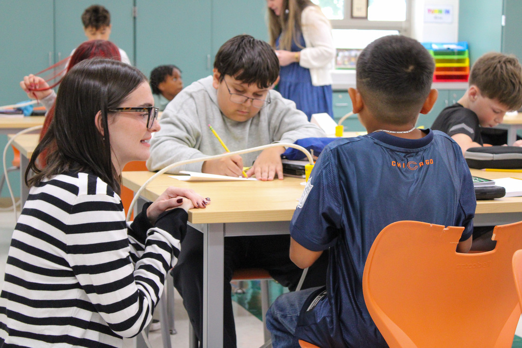 teachers talking to student seated at table