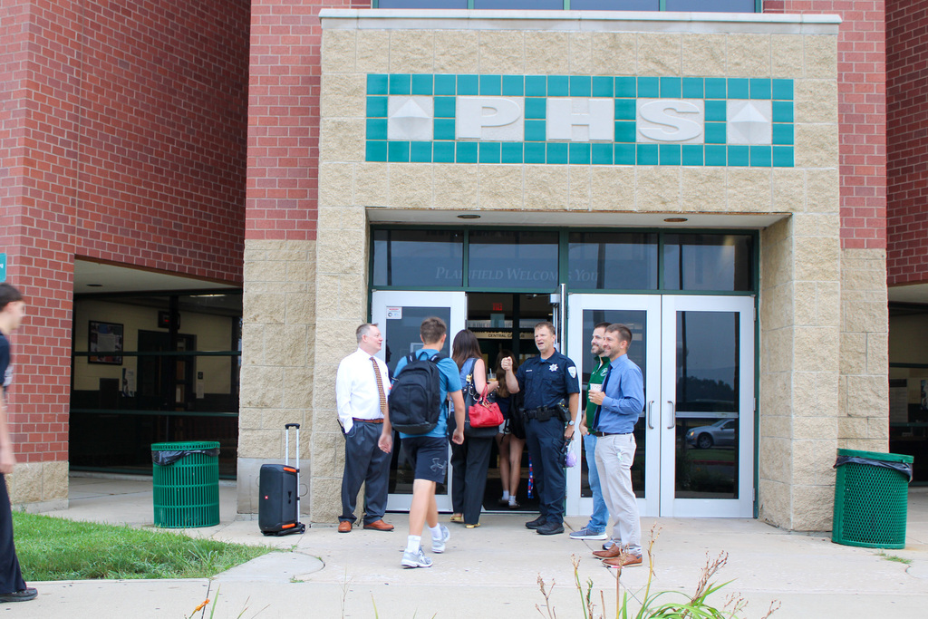 high school students walk into PHS school building