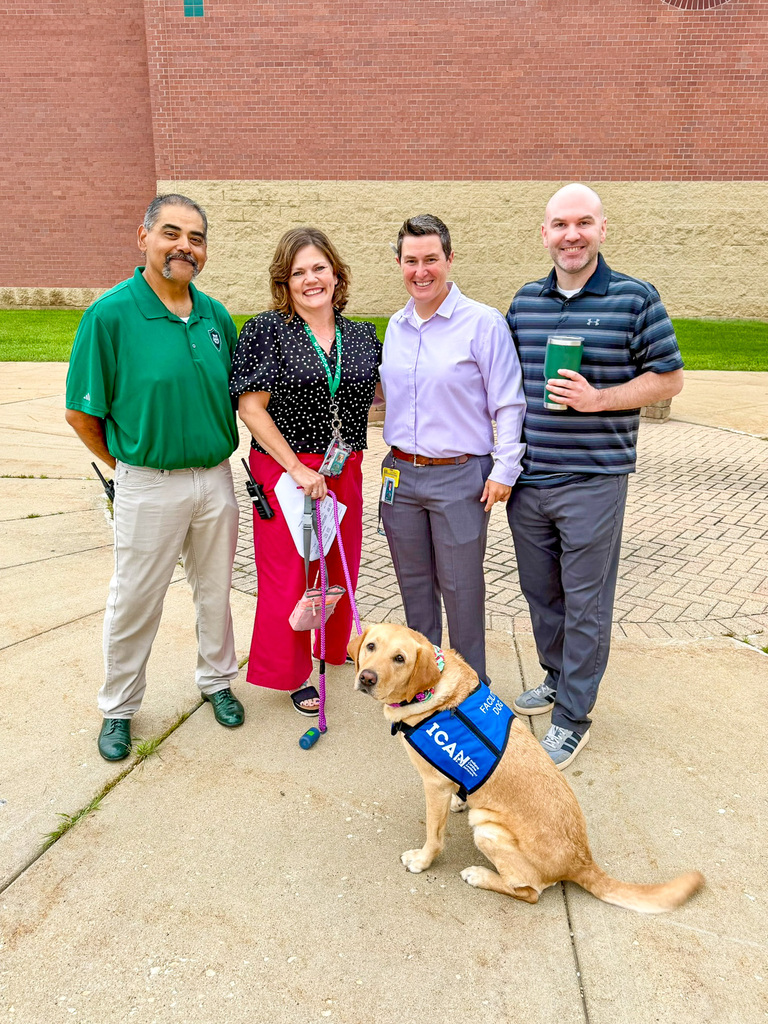group of teachers, administrators stand with facility dog Mooch