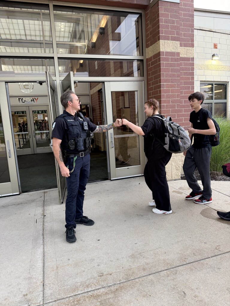 Officer high fives student walking into building