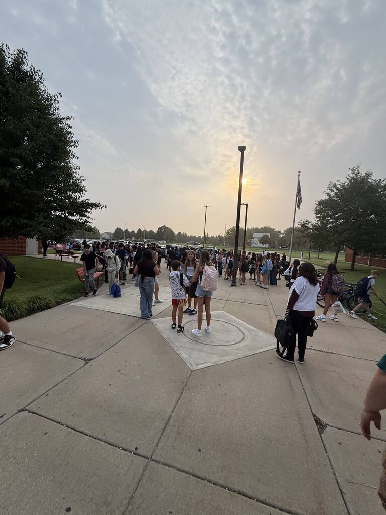 students walking into building sunrise in background