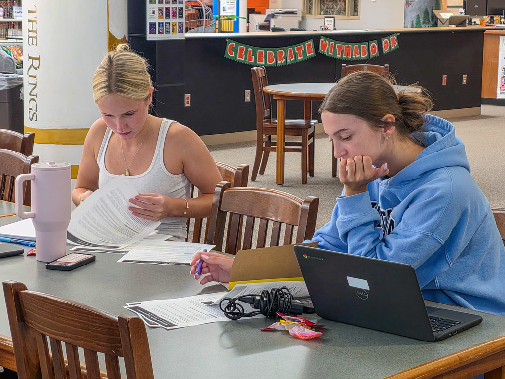 students working on laptops, writing in notebooks