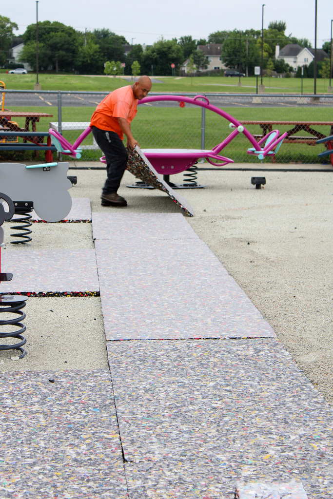 man pulling foam mat onto gravel floor