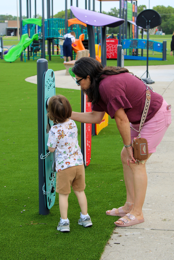 a teacher and child play with a newly installed piece of equipment