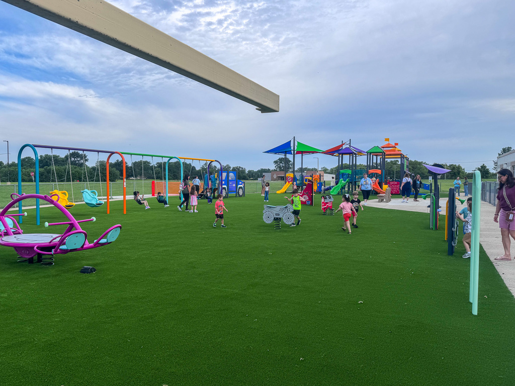 new playground with green turf and kids playing on it