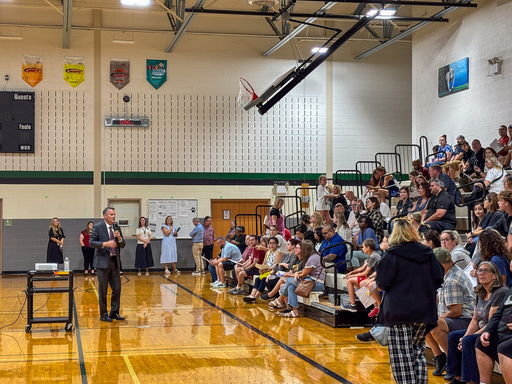 man talking to group of people sitting in bleachers